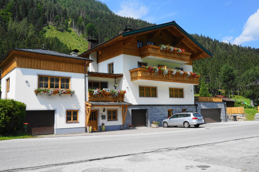 Fassade mit dunklem Holz und verblichener Farbe nach den Renovierungsarbeiten. Jetzt mit hellem Holz und schöner Farbe.